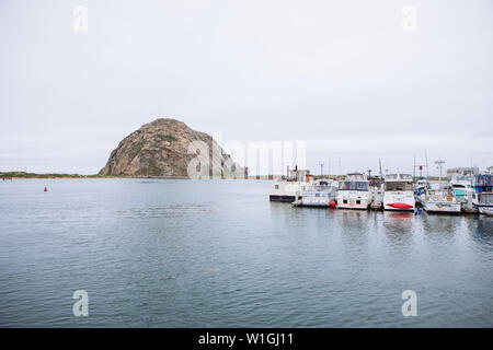 Boote in den Docks und Morro Rock in Morro Bay Beach, bewölktes Wetter, Kalifornien, USA Stockfoto