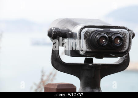 Verwitterte binocular Teleskop auf einem drehbaren Sockel montiert auf einem Berg in Busan city, Republik Korea Stockfoto