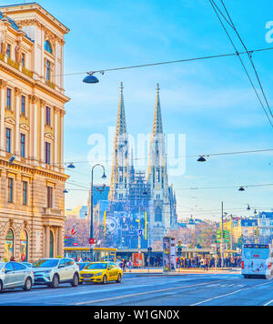 Wien, Österreich - 18. FEBRUAR 2019: Die hohen Türme der Glockentürme der neo-gotischen Votivkirche (Votivkirche) mit einer urbanen Aktivitäten auf die Straßenbahn Statio Stockfoto