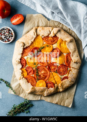 Herzhafte Frische hausgemachte Tomatentarte oder Galette. Ideen und Rezepte für gesundes Mittagessen, appetiezer - ganze Weizen oder Roggen - Weizen Torte mit Tomaten, Parmesan, Mozzarella. Ernte Tomaten. Flach. Vertikale Stockfoto