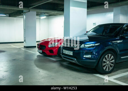 Seoul, Südkorea - 03.11.18: Blue Range Rover in der Tiefgarage sind zwei geparkte Autos in der Parkgarage. Stockfoto