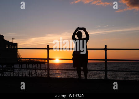 Aberystwyth Wales UK, Dienstag, 02. Juli 2019 UK Wetter: eine Frau nimmt eine selfie, gegen den Himmel ab, während Sie den herrlichen Sonnenuntergang in Aberystwyth auf der Cardigan Bay Küste beobachten, West Wales. Photo Credit: Keith Morris // Alamy leben Nachrichten Stockfoto