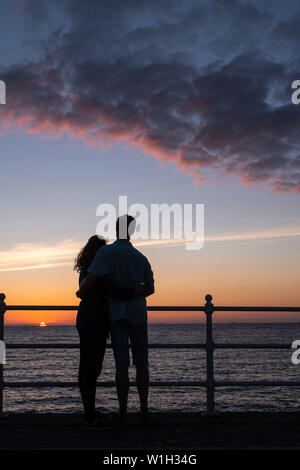 Aberystwyth Wales UK, Dienstag, 02. Juli 2019 UK Wetter: ein Paar Umarmung, gegen den Himmel ab, während Sie den herrlichen Sonnenuntergang in Aberystwyth auf der Cardigan Bay Küste beobachten, West Wales. Photo Credit: Keith Morris // Alamy leben Nachrichten Stockfoto