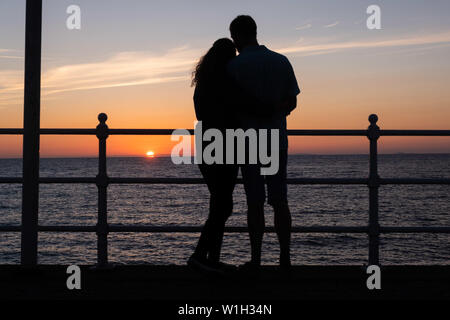 Aberystwyth Wales UK, Dienstag, 02. Juli 2019 UK Wetter: ein Paar Umarmung, gegen den Himmel ab, während Sie den herrlichen Sonnenuntergang in Aberystwyth auf der Cardigan Bay Küste beobachten, West Wales. Photo Credit: Keith Morris // Alamy leben Nachrichten Stockfoto