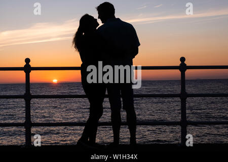 Aberystwyth Wales UK, Dienstag, 02. Juli 2019 UK Wetter: ein Paar Umarmung, gegen den Himmel ab, während Sie den herrlichen Sonnenuntergang in Aberystwyth auf der Cardigan Bay Küste beobachten, West Wales. Photo Credit: Keith Morris // Alamy leben Nachrichten Stockfoto