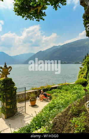 LENNO, Comer See, Italien - JUNI 2019: zwei Personen sitzen auf einer Bank auf dem Gelände der Villa Balbianello in Lenno am Comer See. Stockfoto