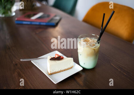 Lecker lecker Kuchen mit Erdbeeren und kaltem Kaffee Frappe mit Eis. Cafe innen im Hintergrund. Stockfoto
