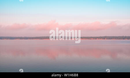 Reflexion der rosa Wolken an einem See. Saylorville Lake, in der Nähe von Polk City, Iowa, USA. Blaue Stunde, Zuckerwatte Wolken, Sonnenaufgang im Mittelwesten. Stockfoto