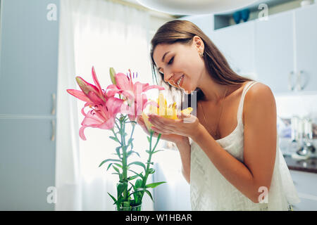 Glückliche Frau Riechen Blumenstrauß aus Lilien. Hausfrau mit Dekor und Einrichtung der Küche. Sweet Home. Allergikerzimmer. Stockfoto