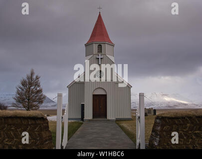 Eine typische Torf Wand vor einem kleinen weißen Kirche in Island Stockfoto