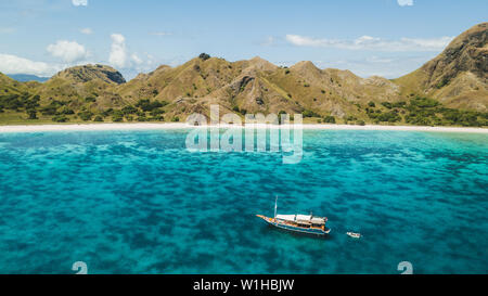 Luxus Kreuzfahrt Yacht segeln über Korallenriff mit erstaunlichen tropischen Strand und Blick auf die Berge. Luftaufnahme. Insel Padar, Komodo Indonesien. Stockfoto