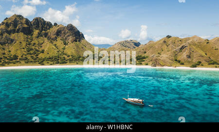 Luxus Kreuzfahrt Yacht segeln über Korallenriff mit erstaunlichen tropischen Strand und Blick auf die Berge. Luftaufnahme. Insel Padar, Komodo Indonesien. Stockfoto