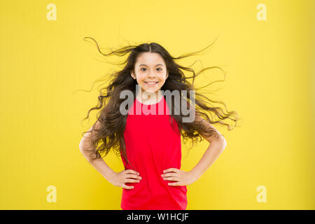 Perfekte locken. Kind süß Gesicht mit adorable curly Frisur. Kleines Mädchen lange Haare wachsen. Teen Mode Modell. Unterschied entdecken. Styling lockiges Haar. Friseur Tipp. Kind Mädchen lange gesund glänzendes Haar. Stockfoto