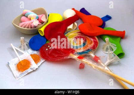 Ein weißer Tisch voller Bonbons, Luftballons, Lutscher und Geleebonbons in vielen lustigen Farben Stockfoto