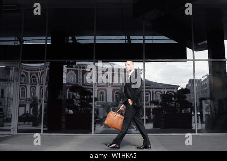 Geschäftsmann mit einer Tasche in der Nähe vom Büro, am Telefon zu sprechen Stockfoto