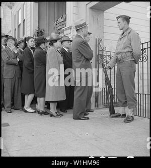 Foto von San Francisco, Kalifornien; Umfang und Inhalt: Original Titel: San Francisco, Kalifornien. Bush Street, San Francisco. Japanische Familie Kopf und allein lebende Personen bilden eine Linie außerhalb der zivilen Kontrolle Station in der japanisch-amerikanischen Bürger Liga Auditorium an 2031 Bush Street, der für die Verarbeitung in Reaktion auf zivile Ausgrenzung Bestellnummer 20 zu erscheinen. Stockfoto