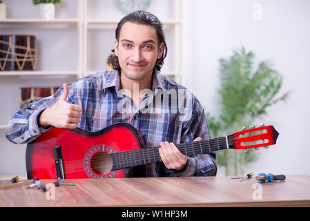 Junge schöne Handwerker Reparatur Gitarre Stockfoto