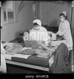 Poston, Arizona. Eingetragene Krankenschwester, Frau Edythe Sasser, ist assisited von Yoshiko Konatsu und Tomiko K. . .; Umfang und Inhalt: Der vollständige Titel für dieses Foto lautet: Poston, Arizona. Eingetragene Krankenschwester, Frau Edythe Sasser, ist assisited von Yoshiko Konatsu und Tomiko Kitasaki, beide Krankenschwester Aids, in der Behandlung der Kinderlähmung. Alle Patienten leiden unter der Dread Disease werden von der Kenny Methode behandelt. Hot Packs sind die betroffenen Gliedmaßen angewendet, und dies wird durch Muskel- und Nervensystem Umerziehung gefolgt. Stockfoto