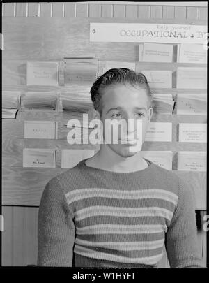 Roosevelt High School, Oakland, Kalifornien. High School Jugend. Von der High School im Juni 1939 graduierte, dieser Junge noch nicht durch Mai 1940 eingesetzt worden. In ein neues Leben Unlaunched, hat er an der High School Bibliothek zurück Zeit lesen aktuelle Zeitschriften zu töten und wieder die vertrauten und sicheren Umgebung eine Umgebung, in der er früher wohl war. Hinter ihm ist ein Rack der beruflichen Broschüren von der National Youth Administration ausgestellt Stockfoto