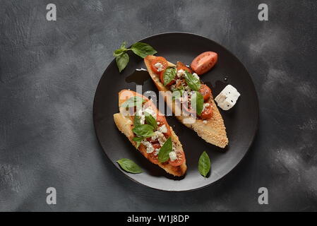 Caprese bruschetta Toasts mit Cocktailtomaten, Mozzarella und Basilikum. Vorspeisen mit italienischen Antipasti, Snacks. Stockfoto