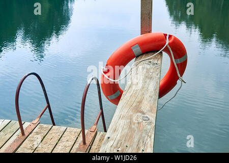 Rettungsring auf einem Pier von einem Wald See an einem bewölkten Tag Stockfoto