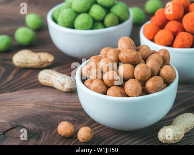 Peanut Snack für Bier, Wein, Party Bar. Gesalzene Erdnüsse in Coconut Glasur auf braune Holztisch. Kopieren Sie Platz. Stockfoto