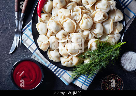 In der Nähe von köstlichen heißen Knödel auf eine schwarze Platte mit Dill und Tomatensauce serviert, Ansicht von oben, flatlay Stockfoto