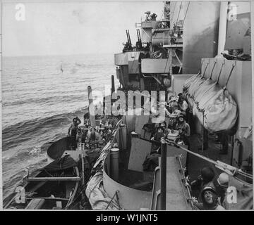 Die Waffe den Besatzungen der Marine Cruiser die amerikanische Landung auf der Insel Mindoro, 15. Dezember 1944, der Himmel in einer Bemühung, ein Flugzeug, um den Overhead zu identifizieren. Zwei 127 mm (5 in.) Gewehre sind bereit, während innen 20 mm Anti-flugzeugbesatzungen bereit sind zu handeln.; Allgemeine Hinweise: Der Cruiser ist USS Phoenix (CL-46), erkennbar an ihrer einzigartigen gesprüht Camouflage 32 Design 5d. Stockfoto