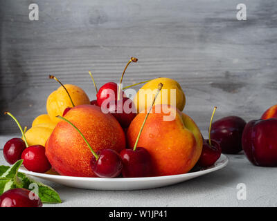 Schöne reife Pfirsiche, Kirschen, Pflaumen, Nektarinen, Aprikosen auf einem hellen Hintergrund. Kopieren Sie Platz. Stockfoto