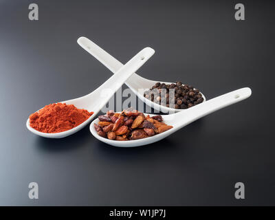 Scharfe Gewürze Löffel in Weiß auf schwarzem Hintergrund Stockfoto
