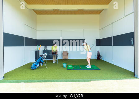 Dedizierte Golftrainer mit moderner Ausrüstung beim Unterrichten einer jungen Frau Stockfoto