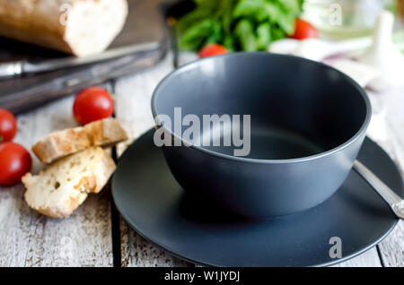Leere schwarze Platte für Abendessen und Besteck auf grauem Beton Hintergrund dienen. Ansicht von oben, kopieren. Stockfoto