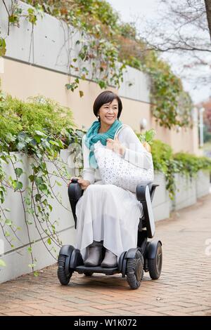 Japanische ältere Frau auf elektrischen Rollstuhl Stockfoto