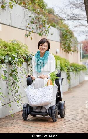 Japanische ältere Frau auf elektrischen Rollstuhl Stockfoto