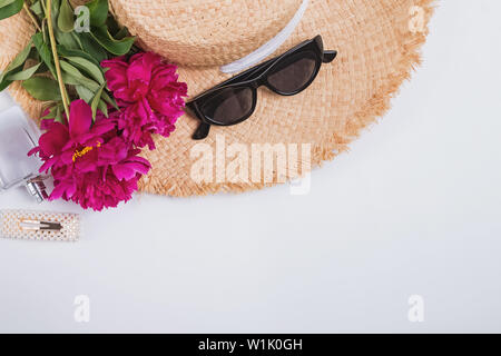 Big staw hat und schöne rosa Pfingstrosen. Kreative Sommer flach. Stockfoto