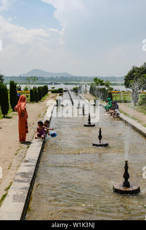 Kinder und Erwachsene genießen in den Strom des Wassers durch Brunnen bei Nishat Bagh, Srinagar, Jammu und Kaschmir, Indien gefüttert. Stockfoto