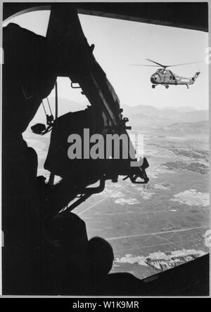 Vietnam: Hubschrauber und Soldat nähert. Viet Nam Foto Service., Ca. 1965; Allgemeine Hinweise: Blick aus der Position der Tür gunner aus einem US Marine Corps Sikorsky UH-34 D Seahorse Hubschrauber von Marine Medium Helikopter Transport Squadron 162 (HM-162) über Vietnam, Ca. 1965. Der Schütze M-60 Machine Gun im Vordergrund, ein anderes UH-34 D im Hintergrund. Stockfoto