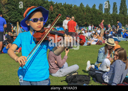 Wimbledon London, UK. 3. Juli 2019. 5 Jahre alte Jimmy spielt die Geige, während sie in der Warteschlange für Tickets im Sonnenschein am Tag drei der Wimbledon Championships. Credit: Amer ghazzal/Alamy leben Nachrichten Stockfoto