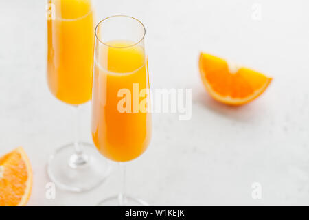 Brunch Mimosa klassische Cocktail aus Orangensaft und Sekt oder Champagner in Flöte Gläser auf einem grauen Tabelle gemacht. Stockfoto