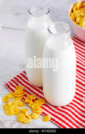 Milchflaschen und Müsli, corn flakes auf hölzernen Tisch. Nahansicht von oben. Stockfoto