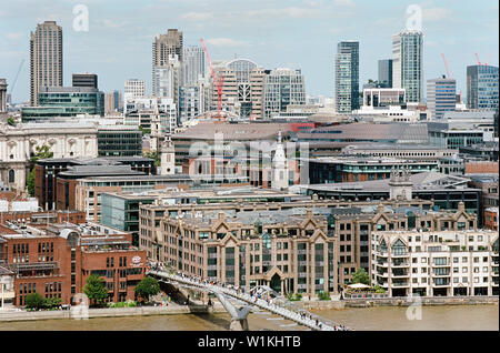 Stadt London und das Barbican gesehen von der obersten Etage des Tate Modern, mit Menschen zu Fuß über die Millennium Bridge Stockfoto