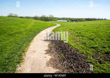 Kurvige weg mit etwas Schlamm in der hügeligen Landschaft auf sonnigen Tag im Frühjahr Stockfoto