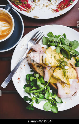 Frühstück mit pochierten Eiern auf Brot mit Salat und Schinken Stockfoto