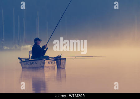 Koronowo / Polen - September 30.2006: Porträt der Fischer in den See im Boot holding Angelrute während der Sunrise in den frühen Morgenstunden Stockfoto