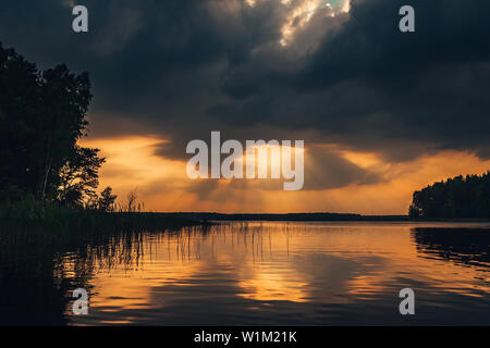 Epische Sonnenuntergang Himmel auf dem See. Schöne Sonnenstrahlen, die durch den dramatischen stürmischen Wolken. Tolle Landschaft. Stockfoto