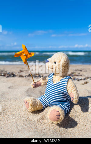 Niedlichen Teddybären in gestreiften Badeanzug glücklich im Sommer Strand mit nostalgischen Spielzeug Mühle (Kopie) Stockfoto