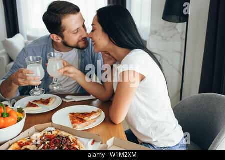 Glückliches Paar küssen und ein Abendessen mit Pizza zu Hause. Es ist eine gute Zeit verbringen Home Stockfoto