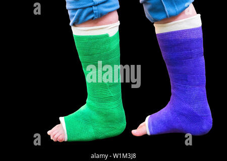 Teenager geht mit zwei bunte Gips Beine auf schwarzem Hintergrund Stockfoto