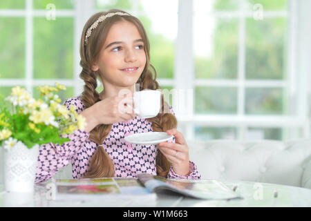 Portrait von cute girl Tee trinken beim Lesen Magazin Stockfoto