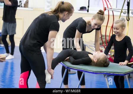 Belarus, Gomel, 4. Juli 2018. Indikative Ausbildung Zirkusschule. Gymnastik Training für Kinder. Der Coach erstreckt sich das Kind an die Gymnastik Garn. Stockfoto